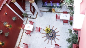 A multi-level outdoor patio with red and white decor, multiple seating areas, and various potted plants. - Ganesha Palace (Amritsar)