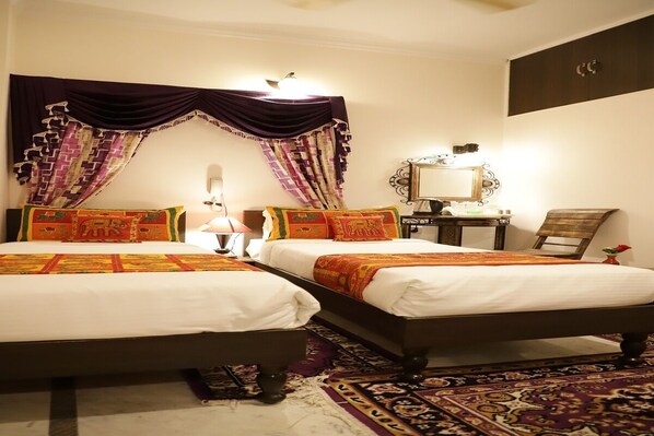 Habitación de hotel con dos camas, una mesita de noche, un espejo y una cortina decorativa.