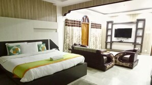 A hotel room with a bed, a sofa, a TV, and a large window.
