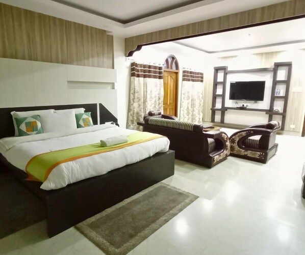 A hotel room with a bed, a sofa, a TV, and a large window.