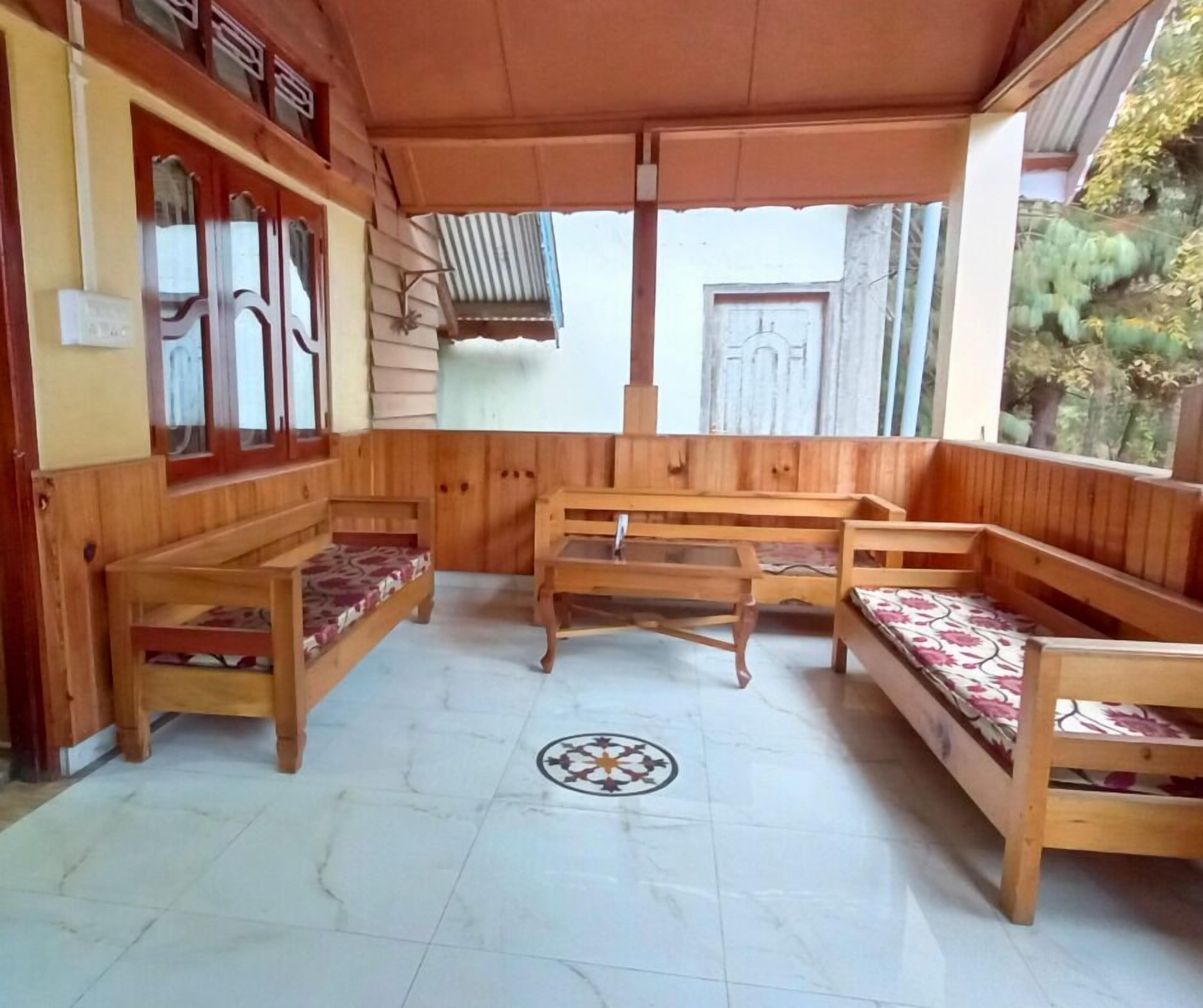 A covered porch with wooden benches and a tiled floor.