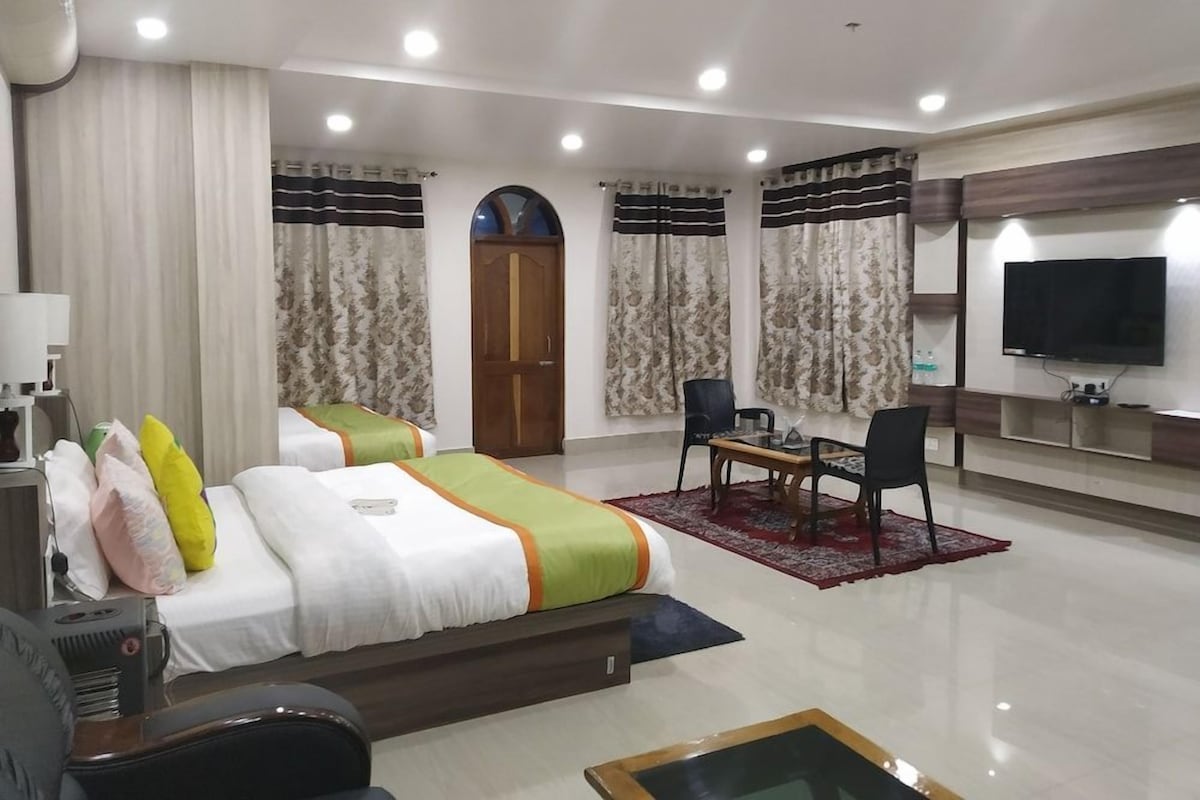 A hotel room with a bed, a desk, a chair, a TV, and a door.