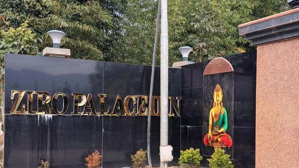 A black wall with gold lettering spelling "ZIORO PALACE IN" and a Buddha statue.