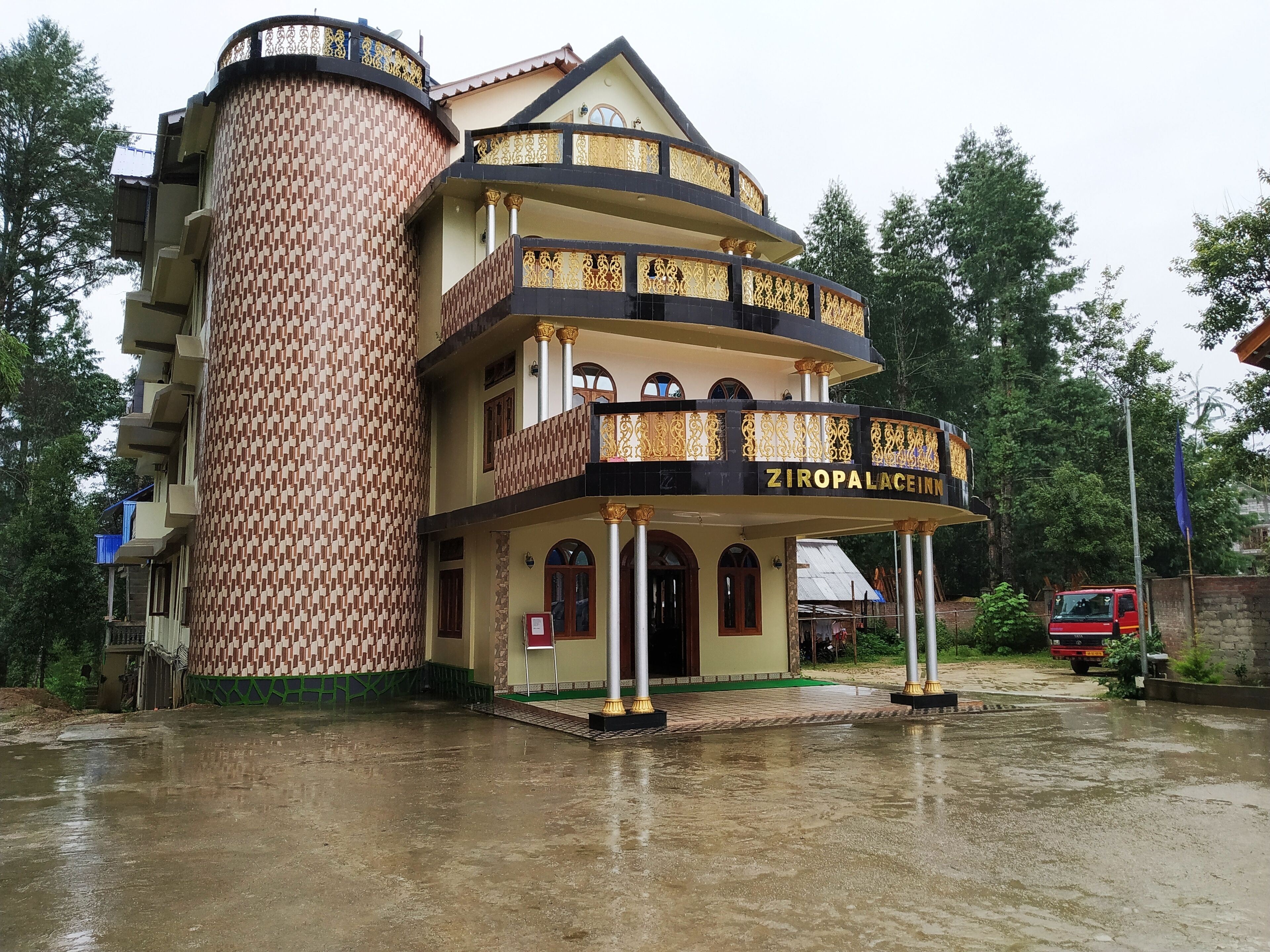 A multi-story building with a distinctive brick pattern and a balcony with golden railings.