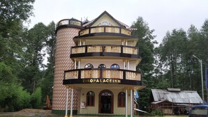 A multi-story building with a distinctive architectural design, featuring balconies with ornate railings and a sign reading "ZIOPALACEINN".