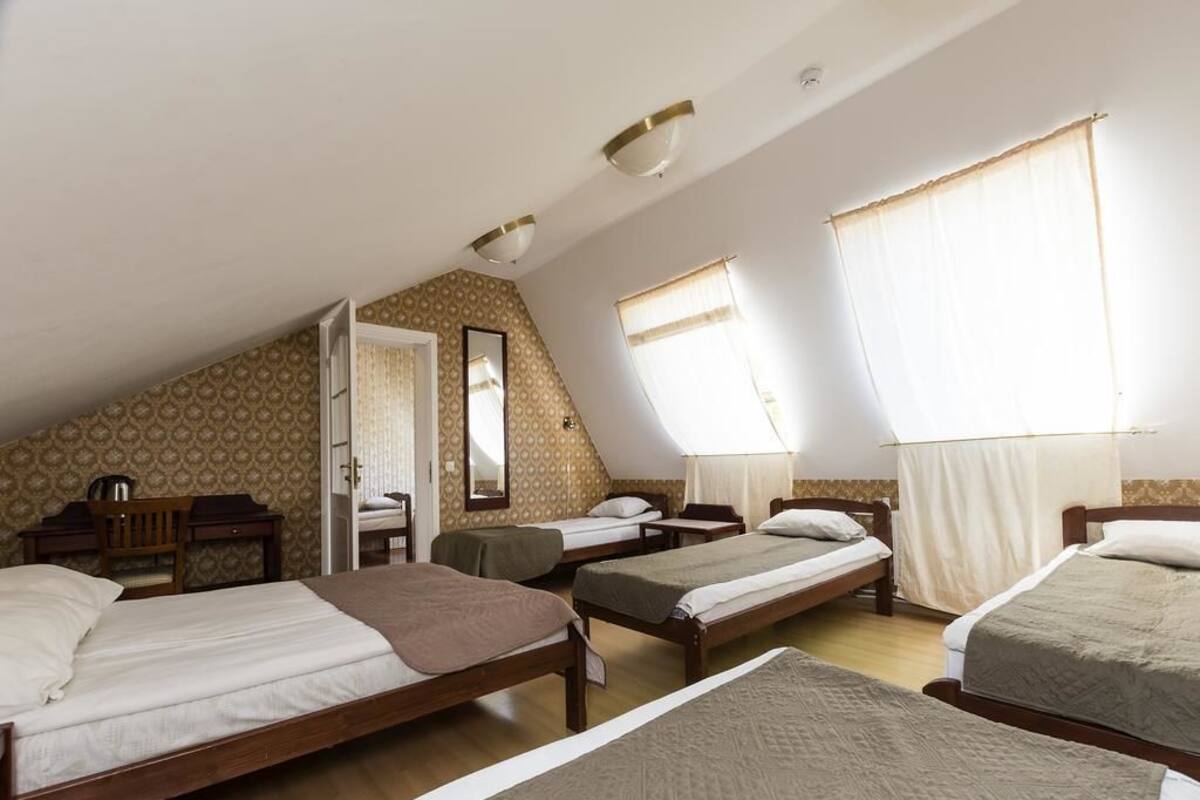 A dormitory room with four single beds, a desk, a chair, and a mirror.