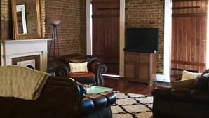 Una sala de estar con chimenea, sofás de cuero, un televisor y una pared de ladrillo.