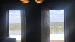 Una habitación con un ventanal grande, piso de madera y sofá de cuero negro.