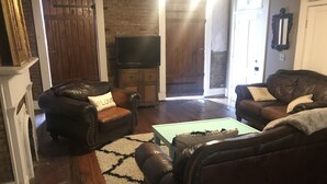 Una sala de estar con dos sofás de cuero, una mesa de centro y un televisor.