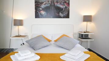 A hotel room with a bed, two nightstands, a cityscape view, and a digital clock on the nightstand.