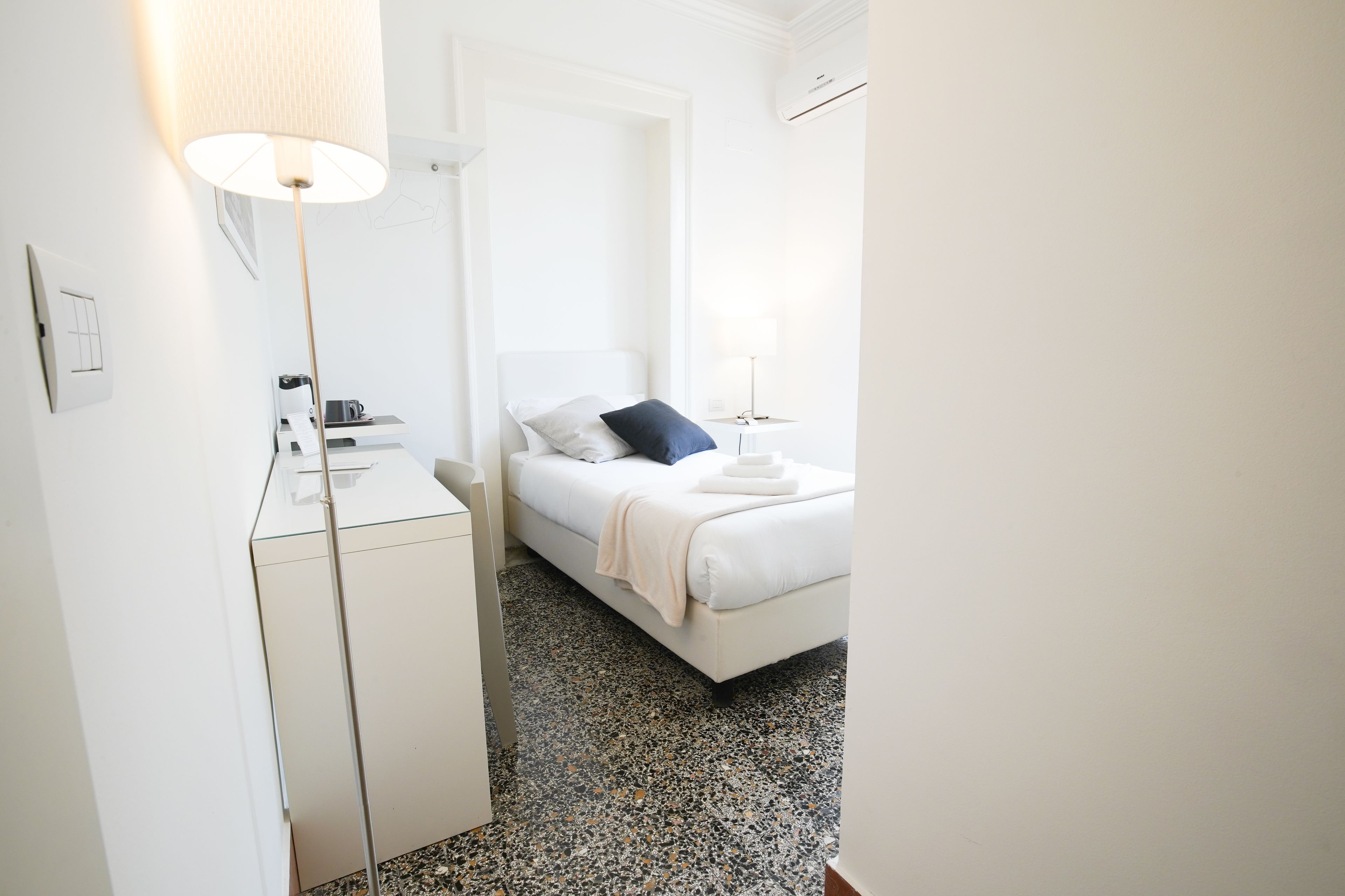 Una habitación de hotel con cama, escritorio, lámpara y cafetera.