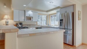Una cocina moderna con gabinetes blancos, un refrigerador de acero inoxidable y un microondas integrado.