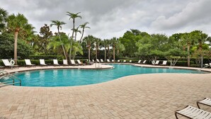 A pool area with lounge chairs and palm trees.