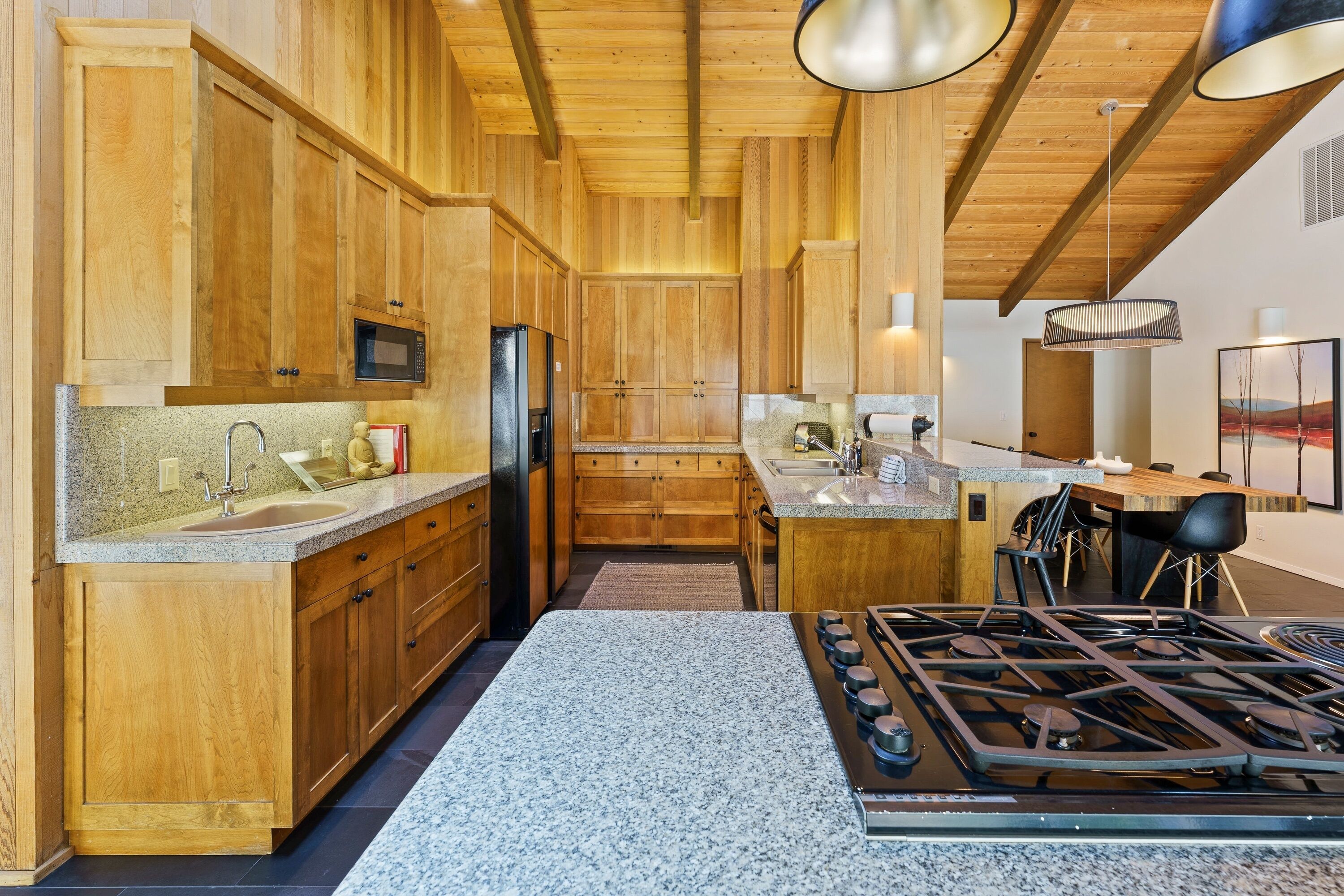 A kitchen with wooden cabinets, granite countertops, a gas stove, and a microwave.
