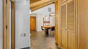 Ein Korridor mit Holztüren, ein Essbereich mit Tisch und Stühlen sowie ein aufgehängter Hirschkopf an der Wand.