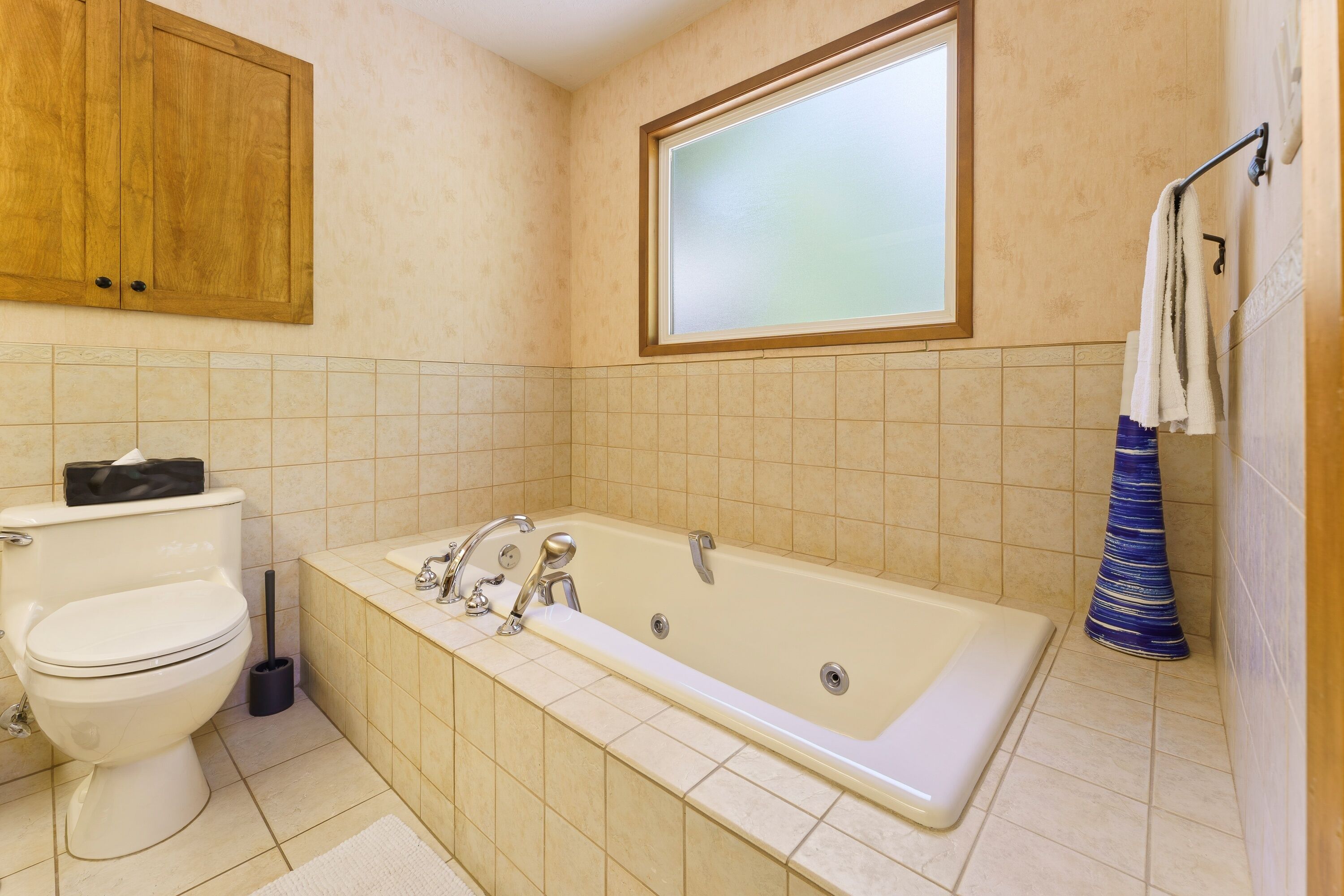 A bathroom with a toilet, a bathtub, and a window.