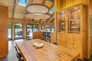 Une cuisine spacieuse avec des meubles en bois, une grande table à manger et un luminaire suspendu.