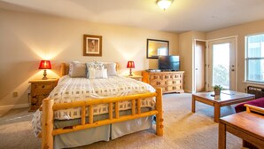 A bedroom with a wooden bed, two bedside tables with lamps, a dresser, a television, and a window with blinds. - Comfortable 09 Lodge Condo Minutes Away from Downtown Hood River by RedAwning (Hood River)