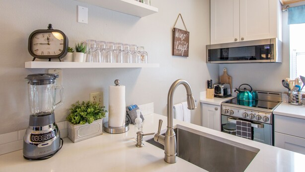 A modern kitchen with white cabinets, a stainless steel sink, a blender, and a microwave. - Comfortable 09 Lodge Condo Minutes Away from Downtown Hood River by RedAwning (Hood River)