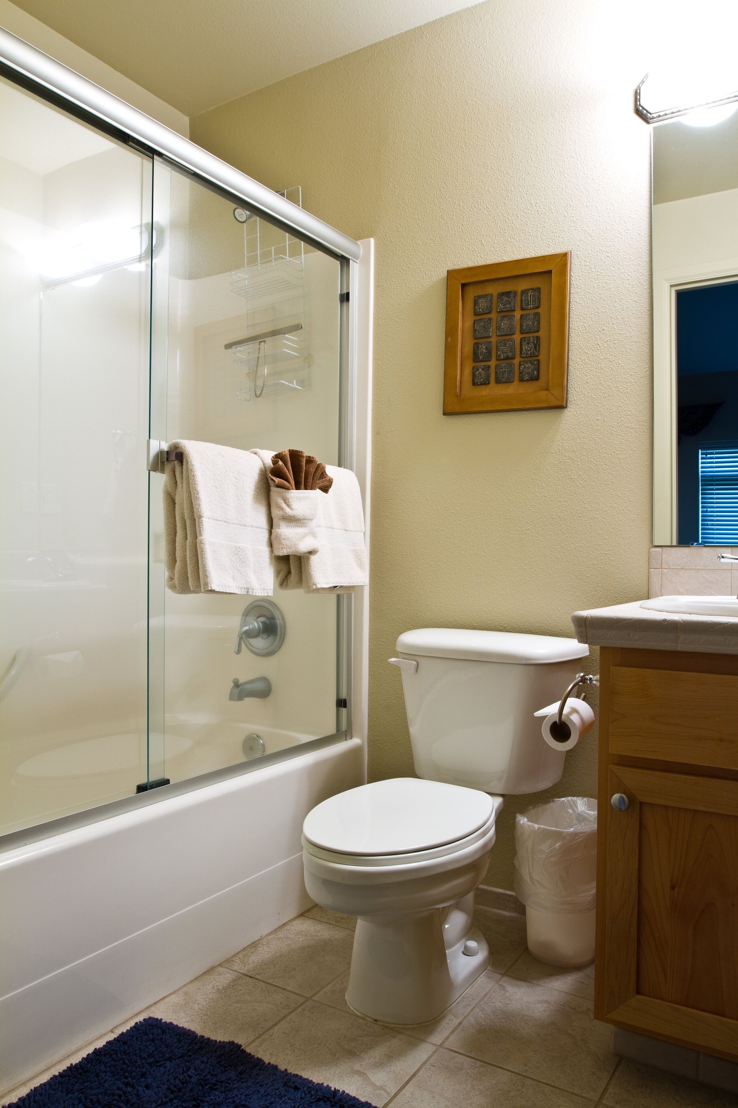 A bathroom with a glass-enclosed shower, a toilet, a sink, and a wooden cabinet.