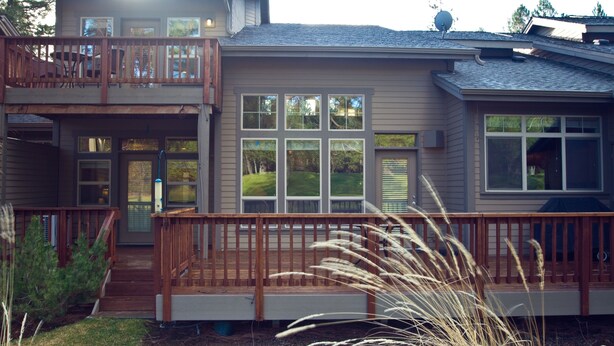 A two-story house with a wooden deck and a covered front porch.