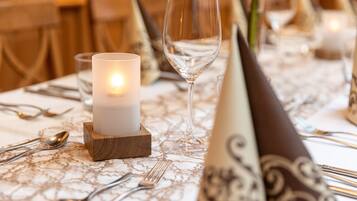 A table set with a candle, wine glass, and silverware on a patterned tablecloth.