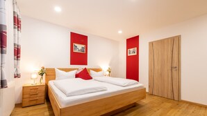 Une chambre à coucher bien rangée, avec un lit en bois, des tables de chevet avec des lampes et une armoire.