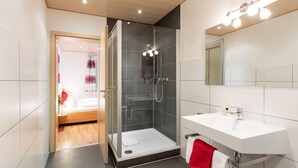 Une salle de bain moderne avec une douche à parois de verre, un lavabo blanc et un miroir avec éclairage intégré.