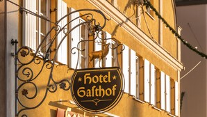 Un hôtel appelé « Hotel Gatthof », reconnaissable à son enseigne distinctive en fer forgé, à son entrée bien visible et à son sol pavé de briques.