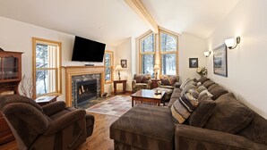 A living room with a fireplace, comfortable seating, and large windows. - 9 Hoodoo Home with XBOX 360 and Private Hot Tub by RedAwning (Bend)