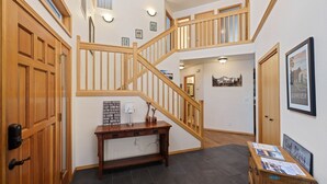 A spacious foyer with a wooden staircase, a console table with a lamp, and framed pictures on the walls. - 9 Hoodoo Home with XBOX 360 and Private Hot Tub by RedAwning (Bend)