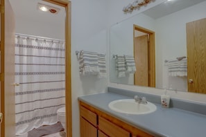 Un baño con cortina de ducha, lavabo, espejo y toallas.