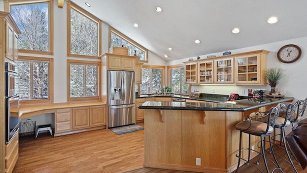 A spacious kitchen with wooden cabinets, a stainless steel refrigerator, and a large island with bar stools. - 2 Sarazen Home with Hot Tub and BBQ on the Deck, Close to Woodlands Golf Course by RedAwning (Bend)
