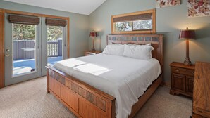 A bedroom with a large bed, wooden headboard, two bedside tables, a nightstand, and a window with blinds. - 2 Sarazen Home with Hot Tub and BBQ on the Deck, Close to Woodlands Golf Course by RedAwning (Bend)