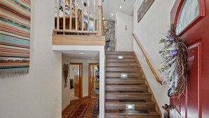 A staircase with wooden steps and a red door, leading to a second floor with a balcony. - 2 Sarazen Home with Hot Tub and BBQ on the Deck, Close to Woodlands Golf Course by RedAwning (Bend)