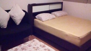 Un dormitorio pequeño y ordenado, con una cama, una mesita de noche y una mesa.