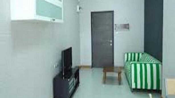 Una habitación pequeña y poco amueblada con una cama individual, un televisor y una puerta.