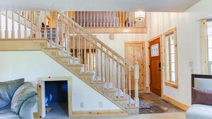 Ein geräumiges Wohnzimmer mit einer Holztreppe, einer Katzentür und einem gemütlichen Sofa.