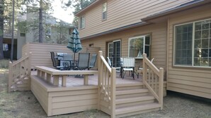 Eine Terrasse mit Gartenmöbeln und einer Holztreppe, die zu einem Haus mit großen Fenstern führt.