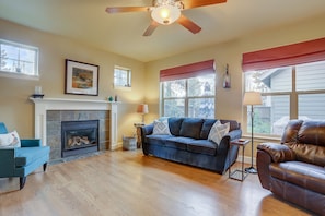 Cozy living room with a fireplace, comfortable seating, and a large window offering a view of the outside.