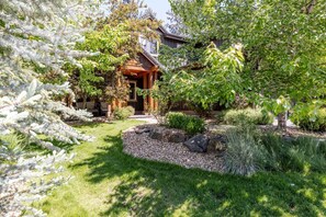 A house with a wooden exterior, a stone pathway, and a well-maintained garden with various plants and a small pond. - Points West 4 Bedroom Townhouse by RedAwning (Bend)