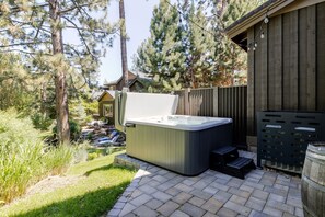 A hot tub in a backyard with a wooden deck, a wooden fence, and a house in the background. - Points West 4 Bedroom Townhouse by RedAwning (Bend)