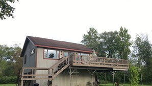 A two-story house with a wooden deck and a covered outdoor area. - Relaxing Elevated Lake House Retreat (Mayville)