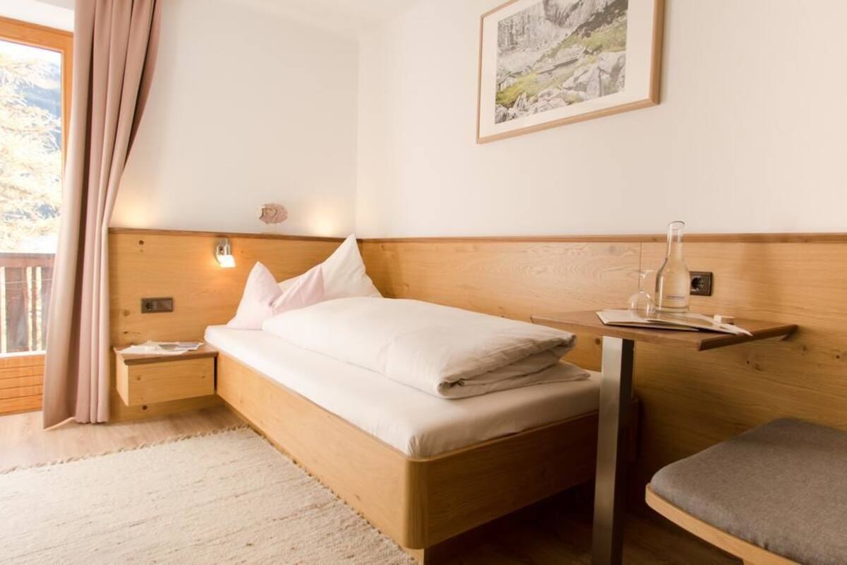 Un dormitorio con una cama de madera, una mesita de noche, una mesilla con lámpara y un cuadro enmarcado en la pared.
