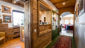 Un interior de madera con una mesa de recepción, cuadros en la pared y una alfombra roja que conduce a un comedor.