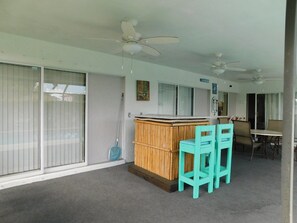 A room with a bar area, two ceiling fans, and a window with blinds. - That One Particular Harbor - Gulf Access Pool Home  3/2 (Cape Coral)