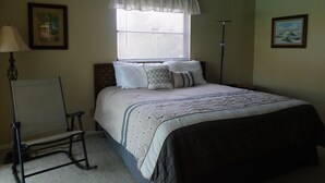 A bedroom with a bed, a standing lamp, a chair, and a ceiling fan. - That One Particular Harbor - Gulf Access Pool Home  3/2 (Cape Coral)