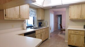 A kitchen with wooden cabinets, a dishwasher, and a ceiling fan. - That One Particular Harbor - Gulf Access Pool Home  3/2 (Cape Coral)