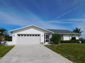 Ein eingeschossiges Haus mit Garage, Rasen und blauem Himmel.