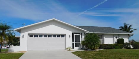 Ein eingeschossiges Haus mit Garage, Rasen und blauem Himmel.